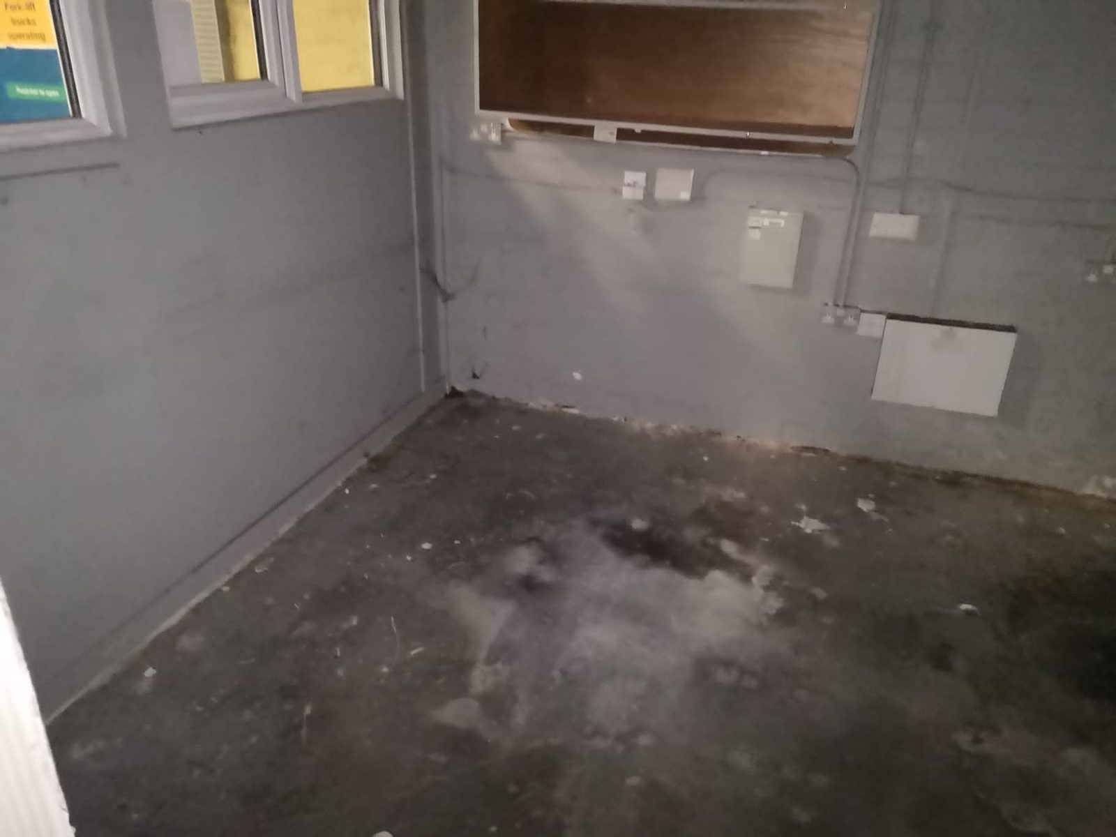Neglected room in a commercial unit with a stained concrete floor and loose fittings